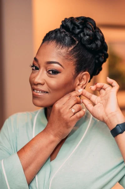 Smiling woman in a bathrobe adjusts her earring with elegance and poise.