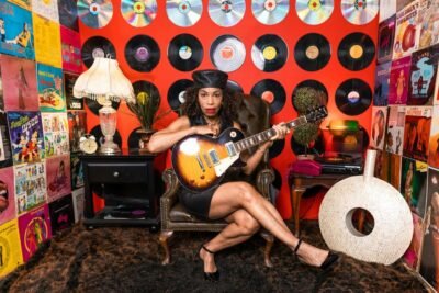 Senior woman with guitar in a vintage decorated room full of records.