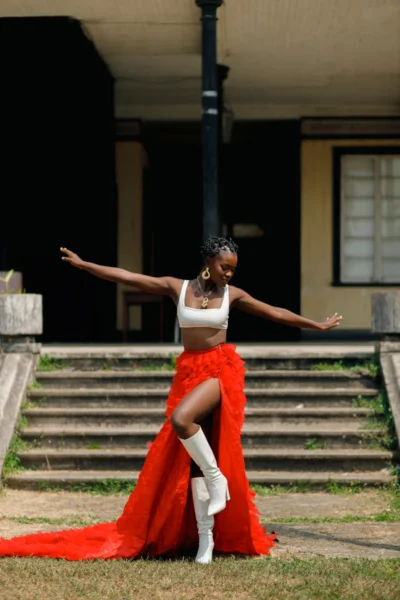 A woman poses gracefully in a red skirt.